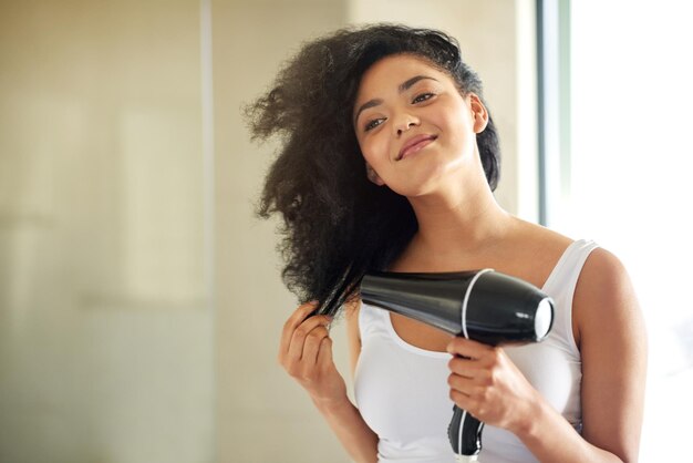 Foto de molhado a cheio e fabuloso foto de uma jovem atraente secando o cabelo com um secador de cabelo em casa