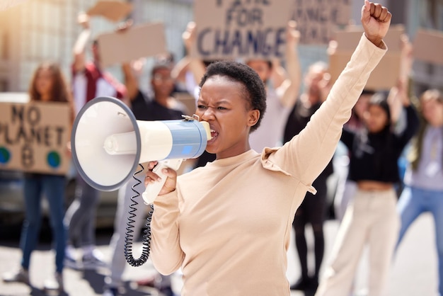 Dê-nos o que queremos. Foto de uma jovem gritando através de um megafone em um protesto.