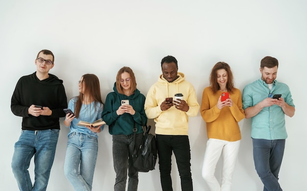 De pé contra um fundo branco Um grupo de jovens está juntos