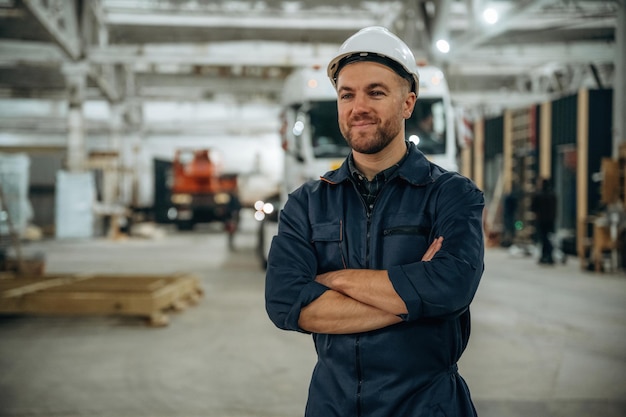De pé em frente a um caminhão Trabalhador masculino está no armazém moderno ou empresa de fabricação