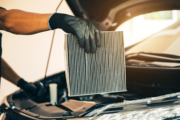 Foto de perto a mão do mecânico de automóveis segurando o filtro de ar do carro