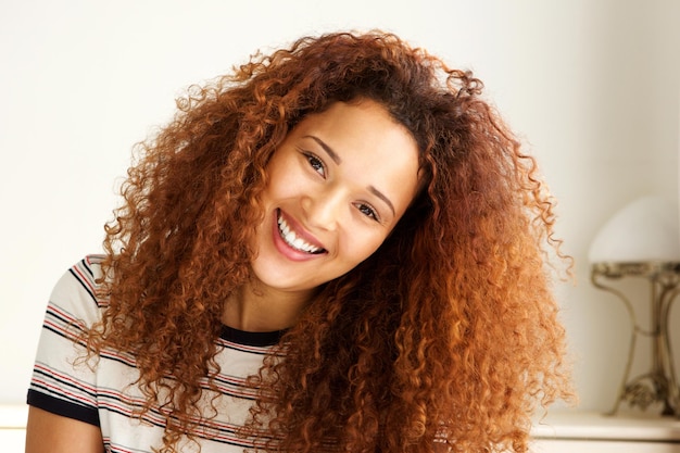 Foto de perto, uma jovem afro-americana feliz a sorrir.