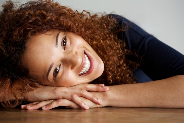 Foto de perto, uma jovem feliz apoiada na secretária e sorrindo.