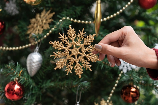 Dé sostener decoraciones del copo de nieve del oro en fondo del árbol de navidad. para Navidad y feliz año nuevo 2020.