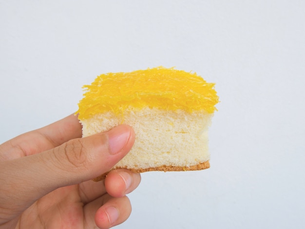 Dé sostener la torta de oro de los hilos (tarta de las pinzas de Foi), postre de Tailandia, fondo blanco.