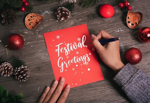 Dé el texto de la Feliz Navidad de la tarjeta de felicitación de la escritura con la decoración de la Navidad en la tabla de madera.