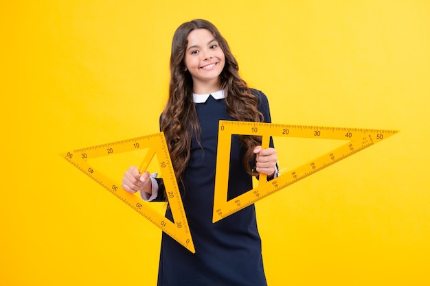 De volta à escola A menina da escola segura a régua medindo isolada no fundo amarelo