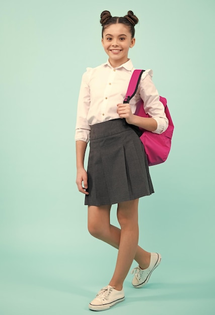 De volta à escola Aluna adolescente em uniforme escolar com mochila Crianças em idade escolar em fundo azul estúdio isolado Feliz adolescente emoções positivas e sorridentes da menina da escola adolescente