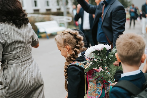 De volta à escola criança feliz aluno estudante oito anos de idade em uniforme de moda com mochila e penteado volumosa longa trança pronta indo para a segunda série primeiro dia na escola primária