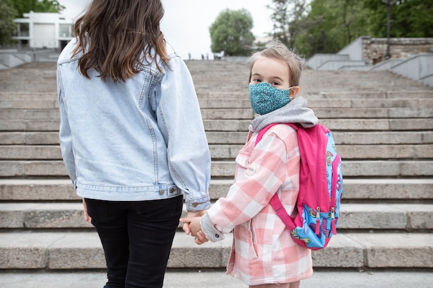 Foto de volta à escola. crianças com pandemia de coronavírus vão para a escola mascaradas. relações amigáveis com minha mãe.