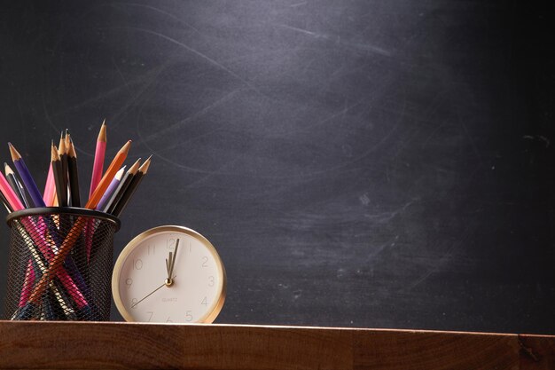 De volta à escola e à educação, porta-lápis e despertador contra o quadro-negro