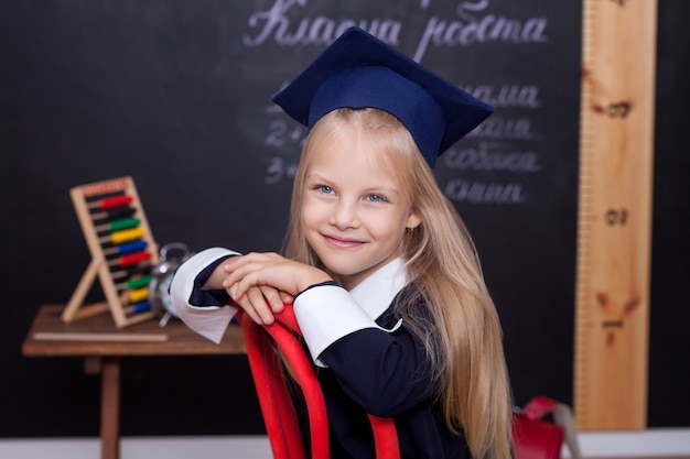 De volta à escola! menina alegre está sentada na aula.