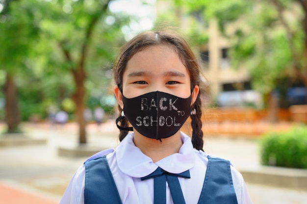 De volta à escola. menina criança asiática usando máscara facial com mochila, indo para a escola. pandemia de coronavírus. Novo estilo de vida normal. Conceito de educação.