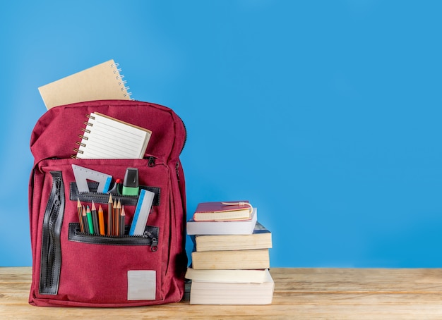 De volta à escola . mochila e suprimentos na mesa de madeira com livros