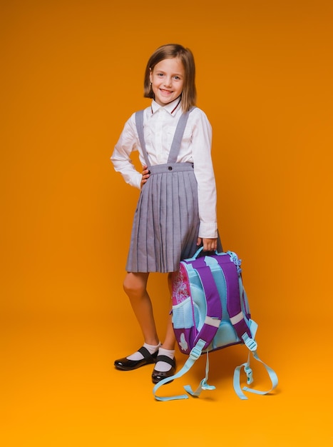 De volta à escola Uma colegial com uma mochila escolar em um fundo de estúdio isolado O conceito de escola e educação Uma adolescente em um uniforme escolar