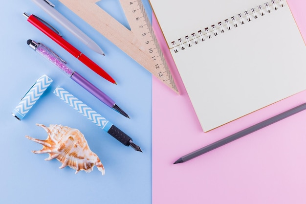 De volta ao conceito da escola Escritório escolar e conchas de mar em fundo rosa-azul Pênis e lápis