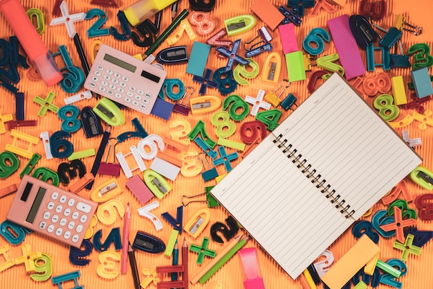 De volta ao conceito da escola. Notebook e equipamentos de educação em fundo laranja.