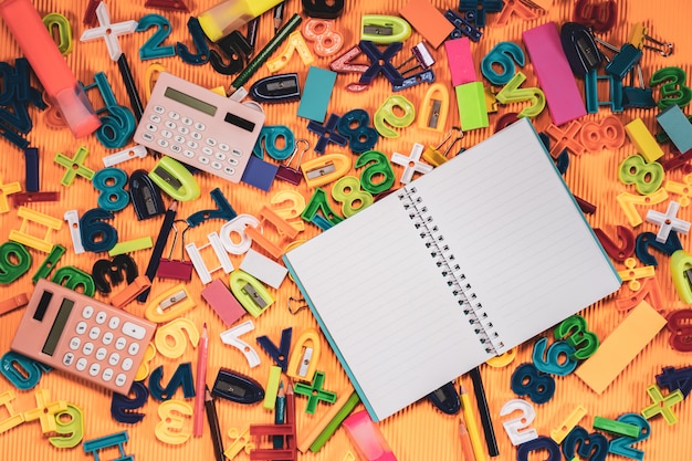 De volta ao conceito da escola. notebook e equipamentos de educação em fundo laranja.