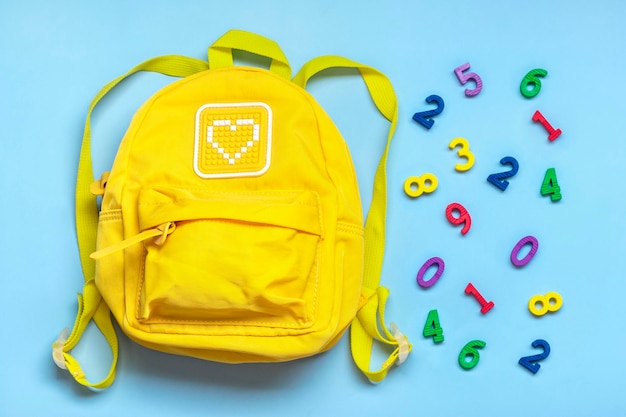 Foto de volta ao conceito de educação escolar números de mochila amarela isolados em fundo azul