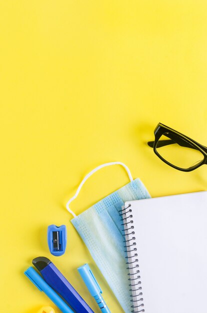 De volta ao conceito de escola. Estojo de lápis com papelaria escolar em um fundo amarelo. papel de caderno, lápis, clipe de papel e nota com espaço de cópia,