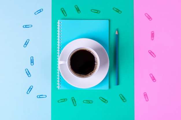 De volta ao conceito de escola ou escritório. Café preto e caderno com o lápis na tabela azul e verde pastel.