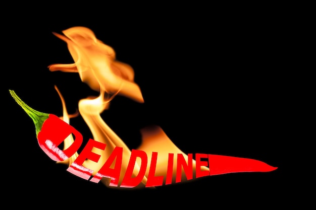 Foto deadline kreativer text auf einer roten scharfen chilischote mit flammenzungen schwarz isolierter hintergrund