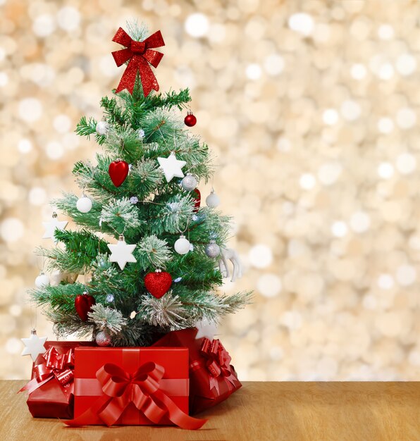 Foto debajo del árbol de navidad decorado hay cajas rojas con regalos.