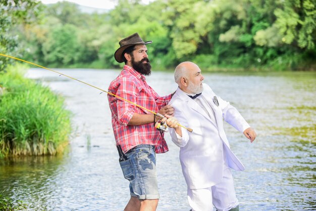 Debe usarlo. empresario jubilado. amistad masculina. familia, abuelo y drandson pescando. pasatiempo y recreación. dos pescadores con carrete de pesca. Fisher hombre maduro celebra la jubilación.