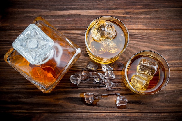 Foto decander y dos copas con hielo y whisky.