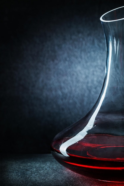 Decantador de cristalería de cocina con vista muy cercana con vino tinto sobre fondo oscuro