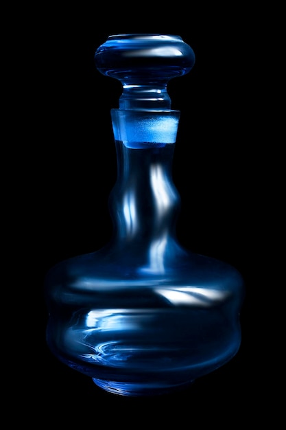 Decantador vacío de vidrio azul vintage aislado sobre negro