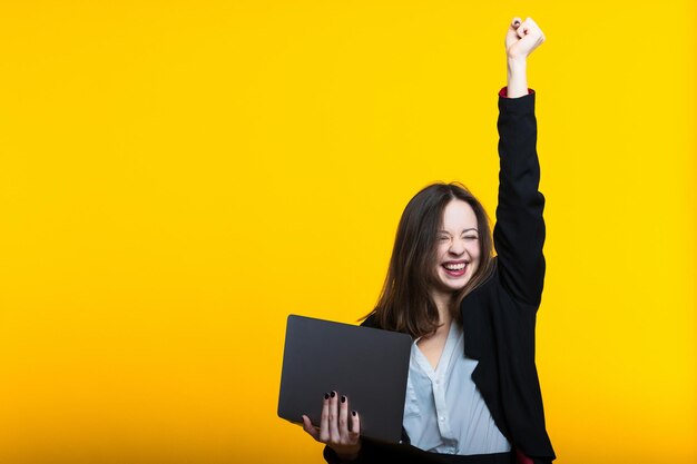 Una decisión exitosa en los negocios. retrato, de, un, mujer joven, con, un, computador portatil, en, un, fondo amarillo