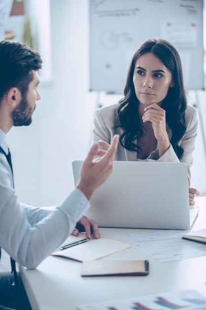 Decisões importantes todos os dias. Dois colegas de trabalho discutindo algo enquanto estão sentados à mesa do escritório