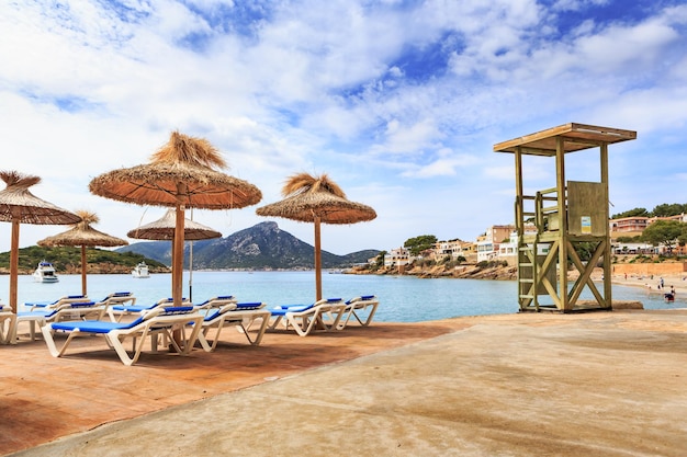Deckstühle mit Regenschirmen am Strand gegen bewölkten Himmel