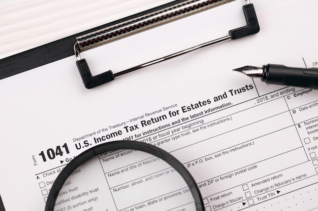 La declaración de impuestos sobre la renta de los Estados Unidos para propiedades y fideicomisos en blanco en una tableta se encuentra en la mesa de la oficina con