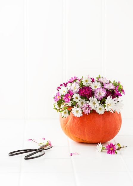 Decoração caseira fácil para o Dia de Ação de Graças com flores coloridas de áster em um vaso de abóbora