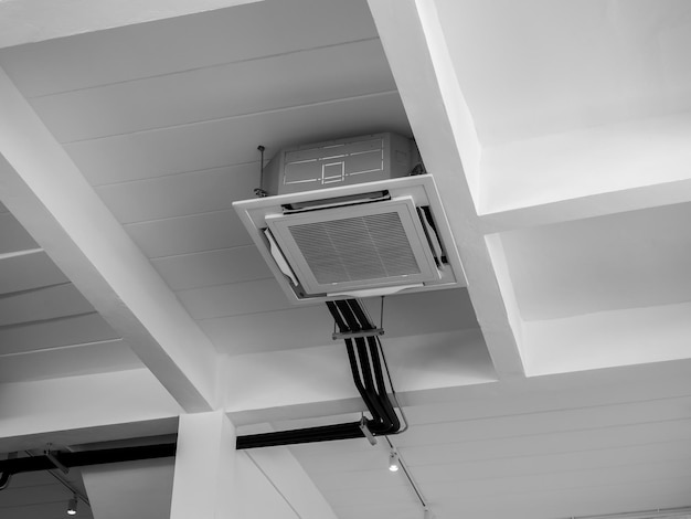 Decoração de ar condicionado tipo cassete montada no teto perto das luzes em construção de concreto branco estilo loft interior Tipo de teto de unidade de ar condicionado com sistema de ventilação