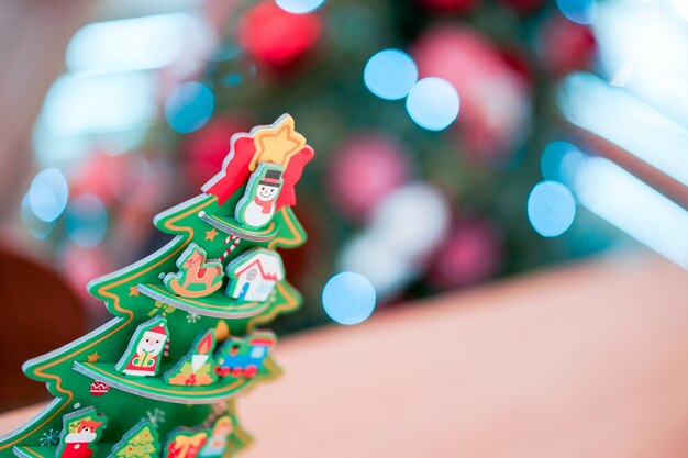 Decoração de artesanato de papel de árvore de Natal na mesa de madeira com borrão de árvore de Natal grande atrás.