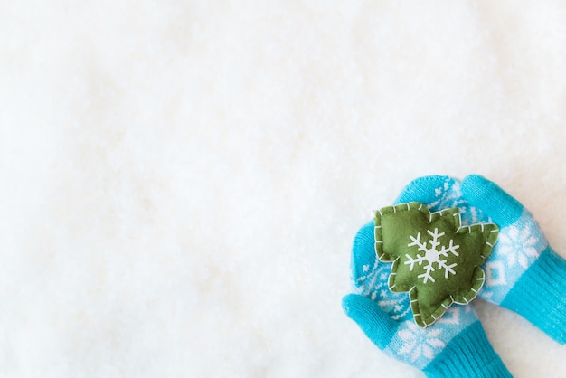 Decoração de árvore de natal em crianças mãos na neve