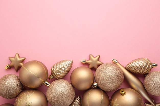 Decoração de brinquedos de Natal de ouro em fundo rosa com espaço de cópia. Cartão de ano novo. Estilo mínimo. Postura plana. Vista do topo