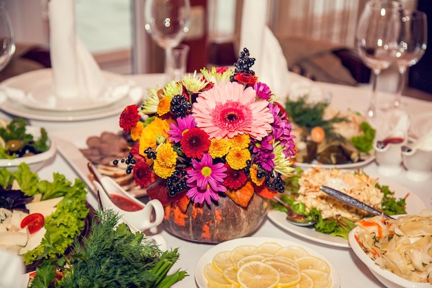 Decoração de casamento de outono em estilo rústico com flores e abóboras nas mesas dos convidados no restaurante em um banquete festivo Arranjo de flores de mesa em um casamento