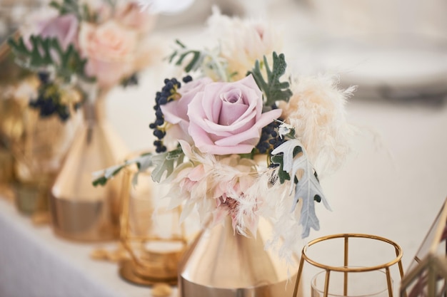 Decoração de casamento em estilo boho Cores claras na tenda Mesa de casamento decorada com vasos de ouro com rosas e cereais E velas geométricas em castiçais de ouro