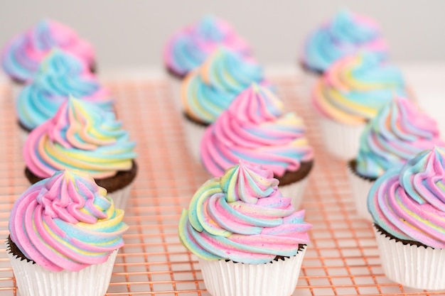 Decoração de cupcakes de unicórnio de chocolate com cobertura colorida de creme de manteiga e granulado.
