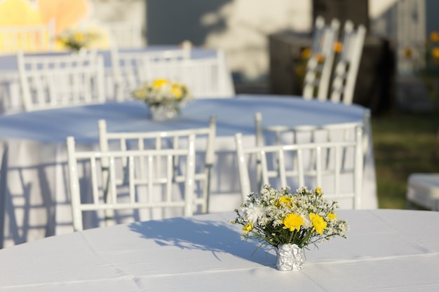 Decoração de flores na mesa branca ao ar livre na recepção do casamento