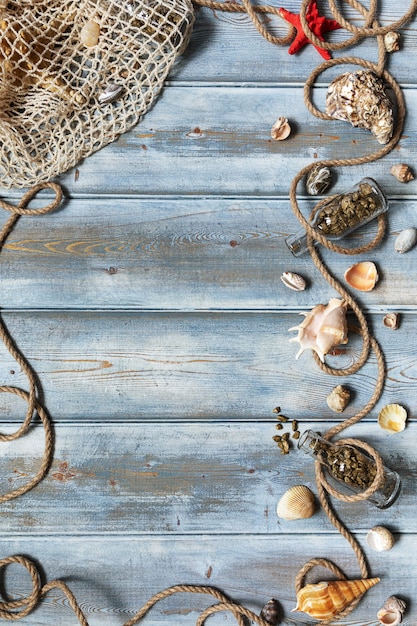 Foto decoração de interiores de verão com estrelas do mar, conchas, cordas e garrafas com pedras sobre fundo azul de madeira. copie o espaço. ainda vida. postura plana