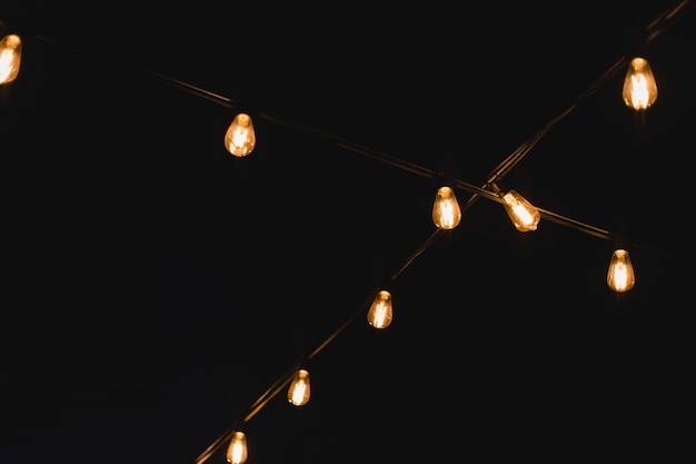 Decoração de lâmpada em festa ao ar livre. Luzes de corda decorativas ao ar livre durante a noite. Guirlanda dourada brilhante em casamento