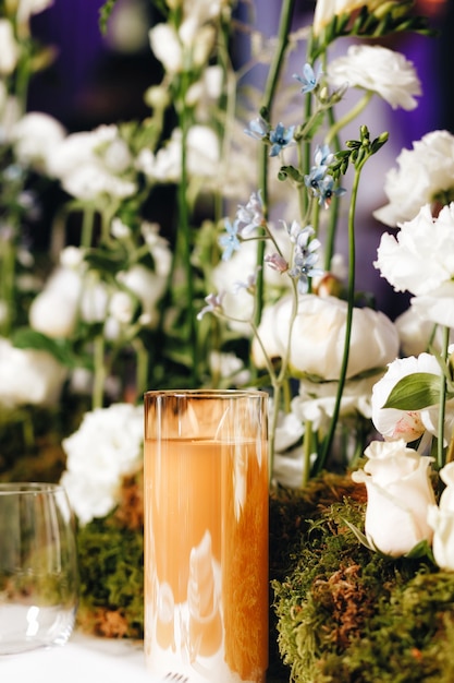 Decoração de layout de mesa de casamento romântico com grandes buquês de flores exuberantes, incluindo rosas brancas, ranúnculos, botões de ouro persas, orquídeas brancas e velas. Foto de alta qualidade