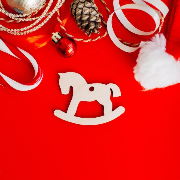 Decoração de madeira na árvore de natal sob a forma dos cavalos de balanço cercados por elementos do natal.