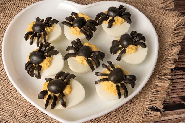 Decoração de mesa de halloween. ovo de aranhas. lanche de festa. num prato branco.