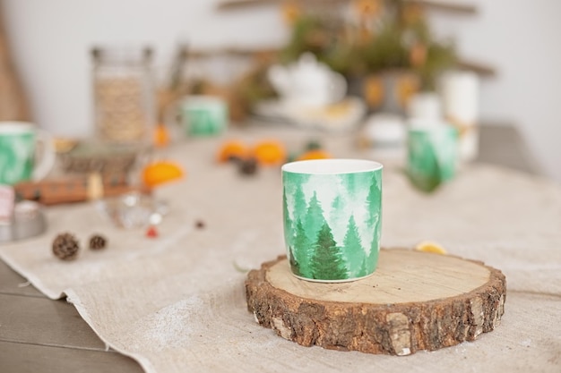 Decoração de mesa de inverno do lado de fora em uma toalha de linho há uma caneca verde de bebida quente em uma árvore cortada